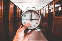 a person holds a clock with wooden doors in the background