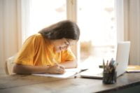 a girl is writing in a notebook