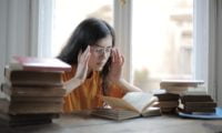 a girl is sitting with books opened