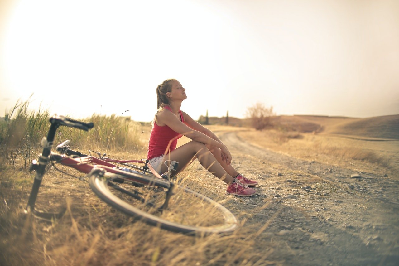 a girl sitting next to her bike